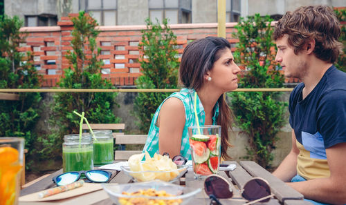 Couple sitting by food and drink at restaurant