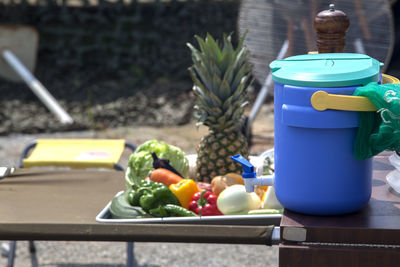 Water container by various fruits and vegetables on table at field