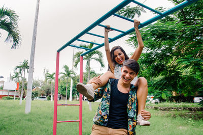 Happy playful friends in park against clear sky