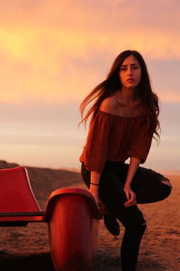 Young woman in red sunglasses against sunset sky