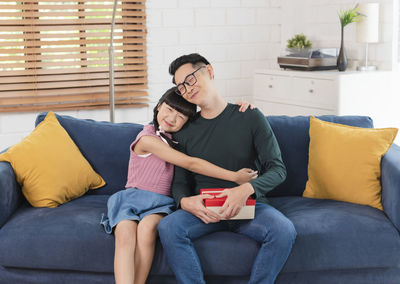 Full length of couple sitting on sofa