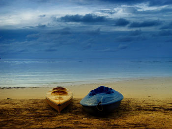 Deck chairs on beach against sky during sunset