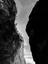 Low angle view of rock formation amidst sea against sky