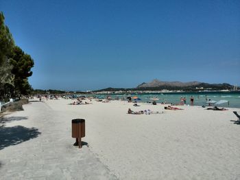 People on beach against clear blue sky