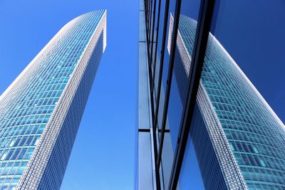 Low angle view of skyscrapers against blue sky