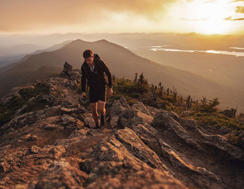 Male hiker walks along appalachian trail on bigelow mountain at sunset