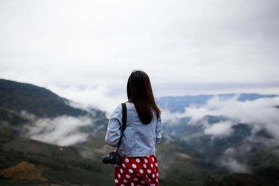 Rear view of woman standing on mountain against sky