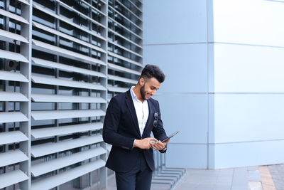 Full length of businessman standing against building