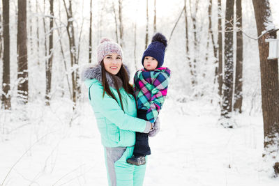 Portrait of smiling young woman standing on snow covered field