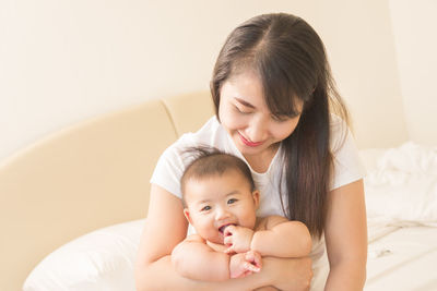 Cute baby girl sitting on bed at home