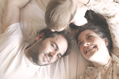 High angle view of family lying on bed