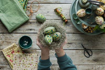 Top view of hands holding nest with easter eggs in kimekomi ornaments style. handmade easter decor