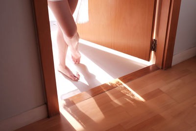 Low section of sensuous woman standing in doorway at home