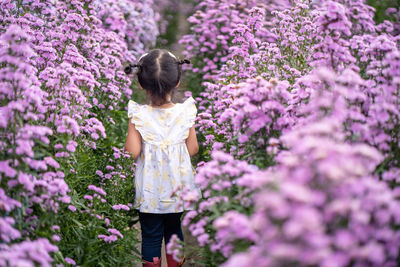 Low angle view of woman standing on pink flowering plants