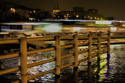 Illuminated bridge over river in city at night