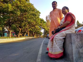 People sitting on road against trees