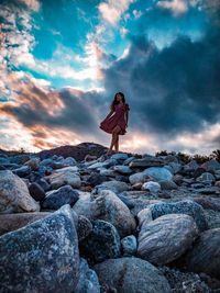 Woman standing on rock against sky