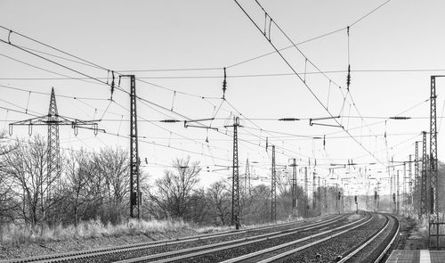 Railroad tracks and electricity pylons against clear sky