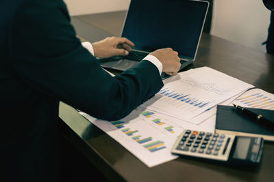 Midsection of businessman working on table