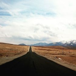 Road amidst desert against sky