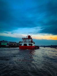 Fishing boat in sea against sky at sunset