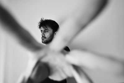 Close-up of man gesturing while looking away standing against wall