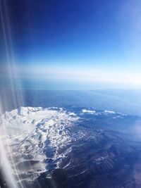 Aerial view of landscape and mountains against blue sky