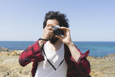 Man photographing on beach against clear sky