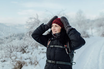 Smiling woman in warm standing on snowcapped mountain