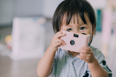 Portrait of boy holding camera at home