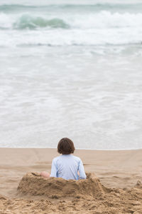 Rear view of woman sitting on beach