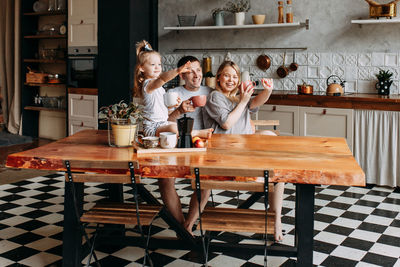 A happy cheerful family with a child is cooking dinner together in the kitchen at home
