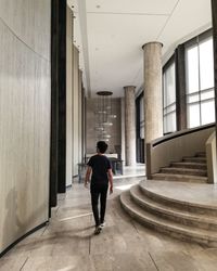 Rear view of man walking in corridor of building