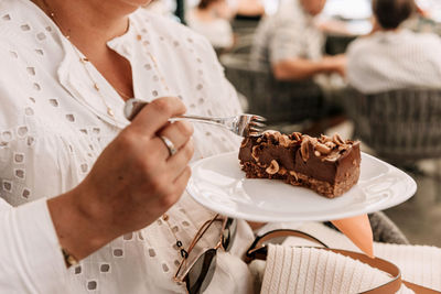 Close-up photo of woman eating delicious cake in cafe