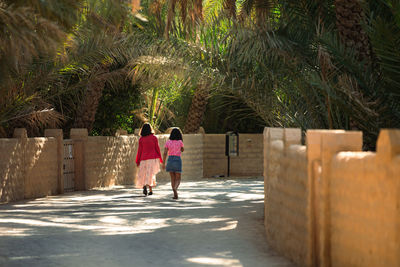 Rear view of couple walking on palm trees