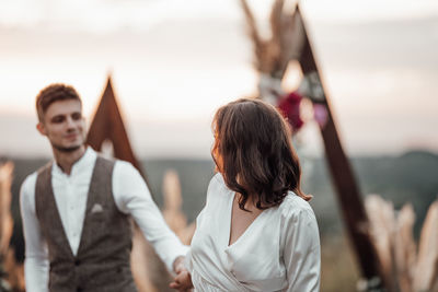 Young couple standing against sky