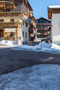 Snow covered street by buildings against sky