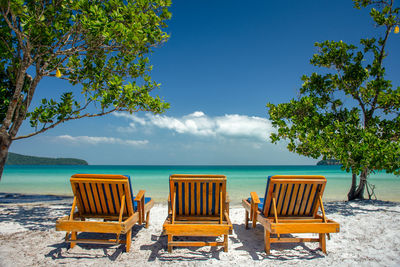 Chairs and tables on beach against sky