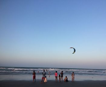 People on beach against clear sky