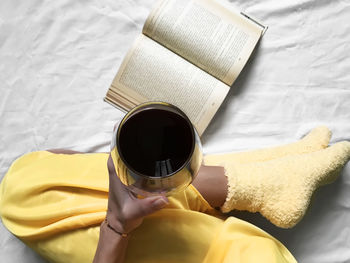 High angle view of person holding book on bed