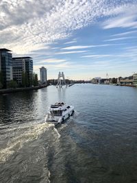 Boat sailing in river against sky in city