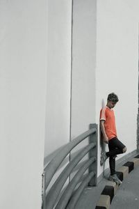 Side view of teenage boy standing against wall