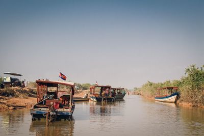 Boats moored on river against clear sky