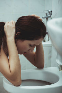 Woman vomiting in toilet bowl