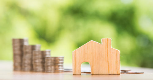 Close-up of model home with coins arranged on wooden table