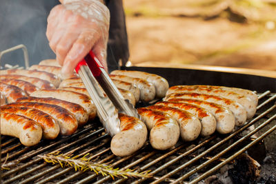 Close-up of person preparing meat on barbecue grill