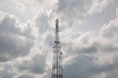 Low angle view of communications tower against cloudy sky