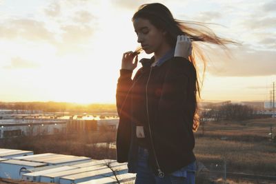 Woman looking at city during sunset