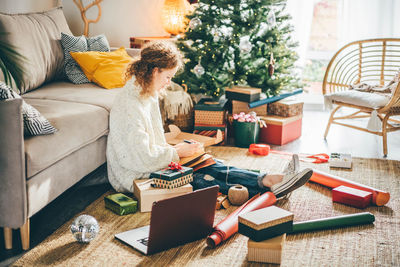 Rear view of woman using digital tablet while sitting at home