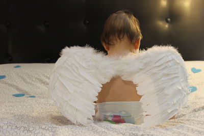 Cute boy sitting on bed at home